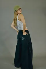 Pantalón de jean negro de corte ancho con pliegues en la parte delantera.