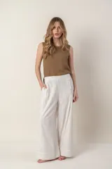 Pantalón ancho de lino color crudo con rayas verticales en tonos celeste, naranja y rosa. Tiene bolsillos laterales y cierre con botones a la vista en el lateral.