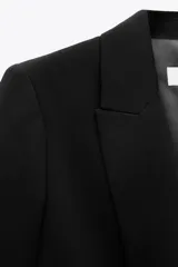 Blazer blanco con cuello solapa y hombreras. Manga por debajo del codo acabada en vuelta con trabilla y botón dorado. Bolsillos delanteros con solapa.