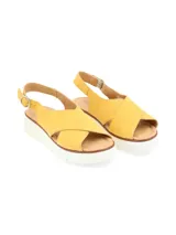 Sandalia amarilla de cuero con tiras cruzadas, suela de plataforma blanca y hebilla metálica de ajuste.