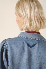 Camisa celeste de tencel, de calce recto, con manga larga amplia con frunces en los hombros y cuello camisero. Mangas terminadas en puño con botón y ojal. Cartera delantera con botones metálicos con el logo de la marca.