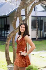 Vestido corto color fucsia con escote en V, breteles finos que se atan al cuello, corte a la altura de la cadera y falda acampanada con ruedo irregular.