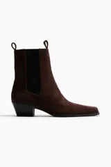 Botas Chelsea de gamuza color marrón oscuro, con punta cuadrada, elásticos laterales negros y taco cuadrado bajo.