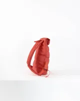 Mochila acolchada color ladrillo con cierre superior enrollable, correas ajustables y logo estampado en blanco.