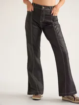 Pantalón de jean negro de corte acampanado, con costuras blancas a contraste y bolsillos delanteros.