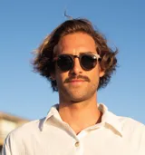 Lentes de sol redondos con marco de madera color marrón oscuro y lentes verdes.