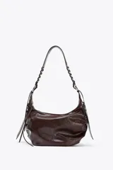 Bolso de hombro marrón oscuro con efecto craquelado, asa con detalles de flecos y anillas metálicas. Incluye bolsillo interior con cierre de cremallera.