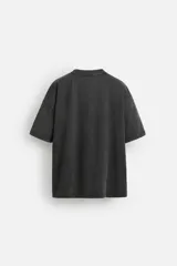 Camiseta negra con efecto lavado, cuello redondo, manga corta y estampado de estrella con texto en el centro.