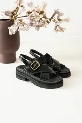 Sandalias bajas color marrón de cuero gamuzado, con tiras cruzadas y hebilla metálica.