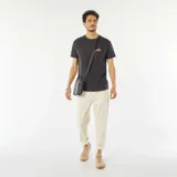Camiseta gris oscuro de manga corta con estampado en la espalda del logo de la lengua de los Rolling Stones con diseño de palmeras en tonos turquesa y rosa.