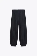 Pantalón bombacho de denim azul oscuro, tiro medio, con bolsillos laterales ocultos y de parche en la espalda. Presenta pinzas en la parte delantera y bajo abullonado con elástico.