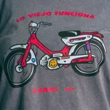 Remera gris de corte oversize con estampa de una moto roja y la frase "Lo Viejo Funciona".