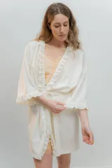 Bata kimono gris claro de algodón con volados en mangas y ruedo. Tiene mangas al codo y lazo de algodón para ajustar en la cintura.