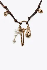 Set de tres collares dorados de diferentes largos. El primero es de eslabones con medalla labrada y perlas. El segundo combina perlas y eslabones con colgantes de medallas labradas. El tercero es de cordón con nudos y charms de diferentes formas.