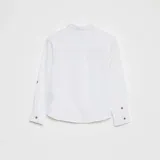 Camisa blanca de lino, de manga larga con cuello mao y abotonadura frontal con botones marrones.