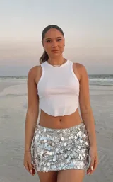 Minifalda plateada con lentejuelas espejadas, tiro bajo, elástico en la cintura y short interno.