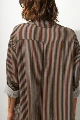 Vestido camisero midi de cuero color marrón, con cuello solapa, manga larga remangada y botones frontales.