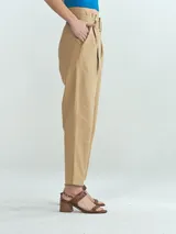 Pantalón de vestir color beige, de corte recto, con pinzas delanteras, bolsillos laterales y cinturón con hebilla forrada.