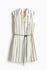 Vestido corto camisero a rayas verticales blancas y negras, con cuello clásico, frente cruzado con botones ocultos y lazo fino negro para atar en la cintura. Sin mangas y con forro.