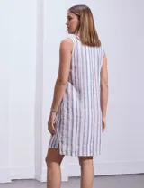 Vestido de algodón a rayas verticales azules y blancas, sin mangas, con cuello a la base y abertura central con lazo de ajuste.
