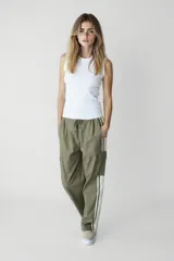 Pantalón negro de corte ancho con cintura elastizada y cordón ajustable. Presenta una franja vertical blanca a lo largo de la pierna y un bolsillo tipo cargo en el muslo.
