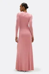 Vestido largo de jersey color rosa, con escote en V profundo y mangas largas. Presenta un drapeado en la parte delantera que se une a una flor bordada a mano.