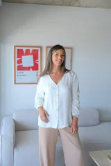 Camisa blanca de manga larga con cuello en V y cierre frontal de botones.