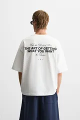 Camiseta negra de corte holgado, cuello redondo y manga corta. Estampado frontal con la frase "Take the risk or lose the chance" en color blanco.