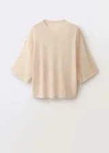 Jersey de punto fino color crema, de manga corta, cuello redondo y corte oversize.