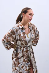 Camisola tipo vestido con estampado floral en tonos marrón, beige y celeste. Tiene cuello camisero, mangas largas y lazo para ajustar en la cintura.