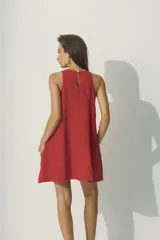 Vestido corto de color negro, sin mangas, con cuello redondo y silueta evasé holgada. Incluye bolsillos laterales.