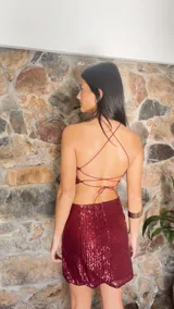 Minivestido borgoña de lentejuelas con escote halter, espalda descubierta y aberturas laterales en la cintura.