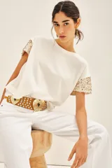 Remera blanca de jersey de algodón con cuello redondo y mangas cortas caídas, bordada con lentejuelas a tono.