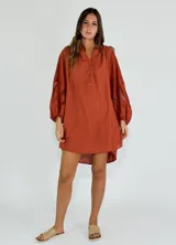 Vestido corto color ocre, con cuello mao, mangas largas abullonadas con detalle de encaje y corte evasé.