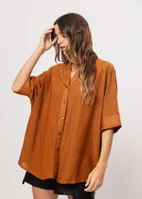 Camisa marrón con calados, escote en V, abotonada y manga 3/4.