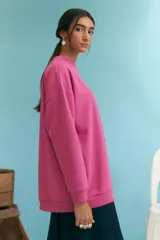 Buzo fucsia de corte holgado, cuello redondo y manga larga.