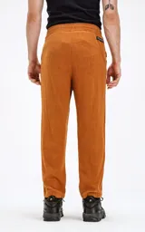 Pantalón de lino color ocre, de corte recto, con cintura elástica ajustable con cordón y bolsillos ribete en el delantero.