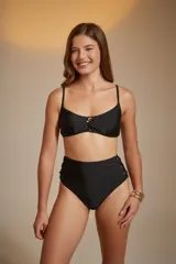 Top de bikini negro con breteles finos y detalle de cordones cruzados en el centro del busto.