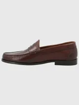 Zapato mocasín de cuero color marrón, con detalle de antifaz y suela de cuero y goma.