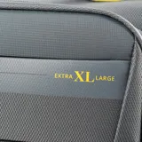 Valija de cabina gris de material textil con detalles en amarillo. Tiene un compartimento interno con cierre, un compartimento externo con cierre, candado TSA y cuatro ruedas. Pesa 2,3 kg.