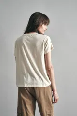 Remera de mangas cortas color crudo, de calce relajado y escote redondo. El frente se encuentra bordado con un diseño de palmeras en lentejuelas y canutillos.