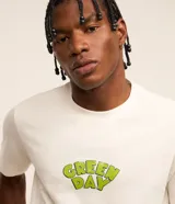Remera color crudo de corte regular, con cuello redondo y mangas cortas. Estampa frontal con el logo de la banda Green Day en color verde.