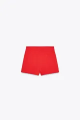 Bermuda roja de tiro alto con bolsillos delanteros de vivo y cierre lateral con cremallera oculta.