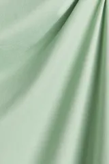 Minivestido verde de punto elástico, con escote asimétrico de un hombro, manga corta con detalle girado y frunces laterales que crean un efecto drapeado suave.