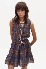 Top sin mangas confeccionado en lino a cuadros color azul, marrón y blanco. Presenta cuello redondo con detalle de puntilla blanca y cierre frontal con botones.