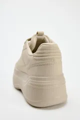 Zapatillas deportivas color beige con plataforma de 6 cm y cierre con cordones.