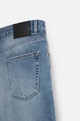 Pantalón de jean celeste con efecto lavado, corte flare fit y caída baggy desde la rodilla hasta el tobillo. Tiene cinco bolsillos y cierre frontal con botones.
