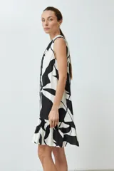 Vestido corto sin mangas, con cuello en V y estampado abstracto en blanco y negro. Tiene cierre frontal con botones y volado en el ruedo.