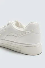 Zapatillas deportivas de estilo retro, color beige y marrón, con cordones y suela gruesa.