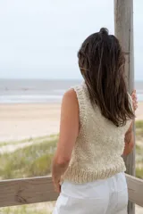 Chaleco tejido color crema, con cuello alto y sin mangas.